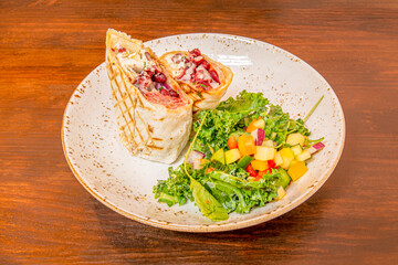 vegan wrap with potato cheese, red beans, tomatoes and chopped fruit salad on kale leaves with olive oil