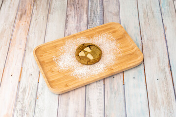 Fototapeta na wymiar cookie with matcha tea dough and white chocolate chips with icing sugar on a bamboo plate
