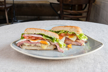 Smoked bacon and meat sandwich with melted cheese, chopped boiled egg, iceberg lettuce and tomato slices
