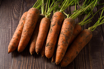a bunch of fresh raw carrots with leaves on table