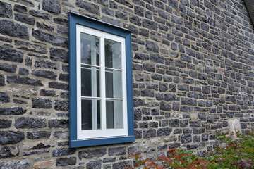 Fototapeta na wymiar Blue and white window on a natural stone wall