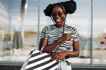 Happy young African American woman wearing black glasses, with black shopping bags