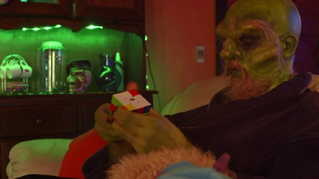 Green monster solving rubik&acute;s cube at home at night, closeup