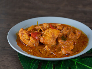 Ayam Kapitan (Kapitan Chicken), Malaysian Curry close up on dark background with copy space. Spicy Asian curry with coconut gravy and chili on wooden table.