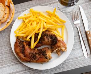 Delicious spicy baked pig trotters with vegetables garnish of crispy french fries on white plate..