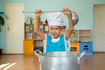 little chef in a hat and a ladle in kindergarten