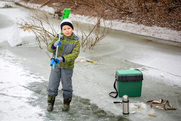 little fisherman stands on ice in winter