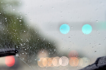 Shot from inside a vehicle looking out through wet glass while passing through traffic during a rain storm