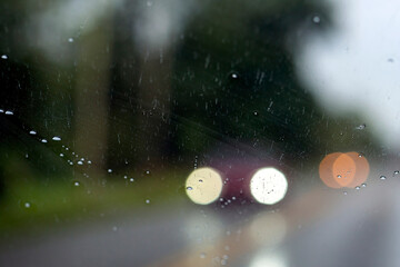Shot from inside a vehicle looking out through wet glass while passing through traffic during a rain storm