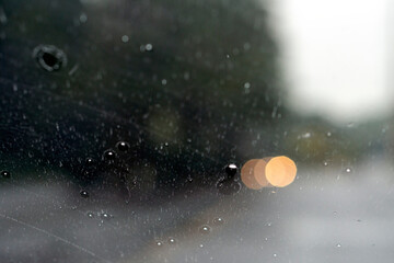 Shot from inside a vehicle looking out through wet glass while passing through traffic during a rain storm