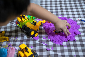 Obraz premium Cropped view of hand cute little boy plays kinetic sand at home.