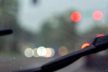 Shot from inside a vehicle looking out through wet glass while passing through traffic during a...