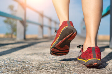 Naklejka premium Woman wear running shoe on to walking and running on nature green background.Health exercise.