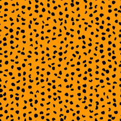 Abstract seamless pattern from small shapes. Simple background of irregular spots. Abstract wild animal skin print. Random spaced black spots. Vector illustration on orange background