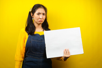 Fototapeta na wymiar Pretty and cute young woman sad, hand holding blank empty banner, placard, white board, blank sign board, white advertisement board, presenting something in copy space, promotion