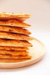 Crop of stack of crispy pizza on wood plate and white background