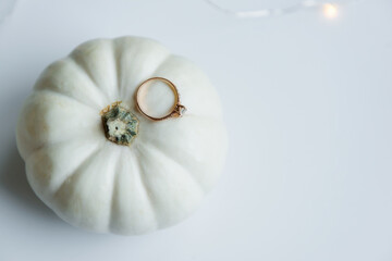 Autumn wedding. There is an engagement ring on the white pumpkin. White isolated background