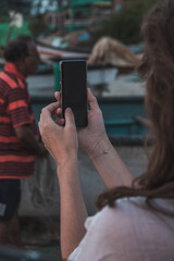 Over shoulder view: woman hands holding black smartphone with blank screen. Mock up, copyspace, template, entertainment and technology concept