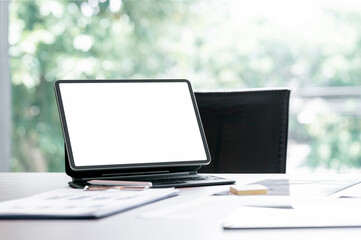Blank screen tablet with magic keyboard and document on the table in modern office room.