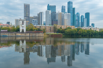 View from the embankment of the Moskva River to a residential area with skyscrapers Moscow City in the background with the reflection of buildings in the water