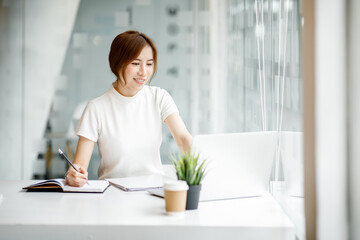 A young woman or businesswoman working on laptop computer in modern office. doing finances, accounting analysis, report data pointing graph Freelance education and technology concept.