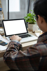Rear view young man using laptop and checking balance and costs at home.