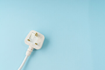 Three pin plug on light blue background with a copy space.