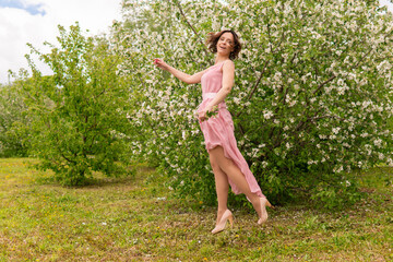 Naklejka na ściany i meble A woman near a blooming spring tree. Romantic happy mood.