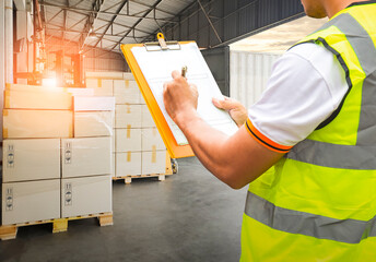 Worker Holding Clipboard is Control Loading Package Box into Cargo Container. Trucks Loading at...