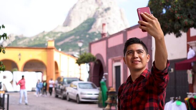 Young man taking a picture with his cell phone while traveling. technology and travel concept.
Latino taking a selfie with cell phone