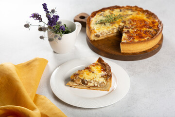 Mushroom quiche with yellow napkin on white table.
