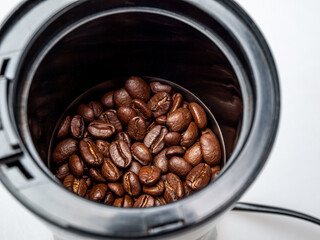 Electric grinder with covered roasted coffee beans, obtaining ground coffee for making a drink,...