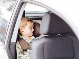 Cute toddler boy sleeping in brown and beige car seat