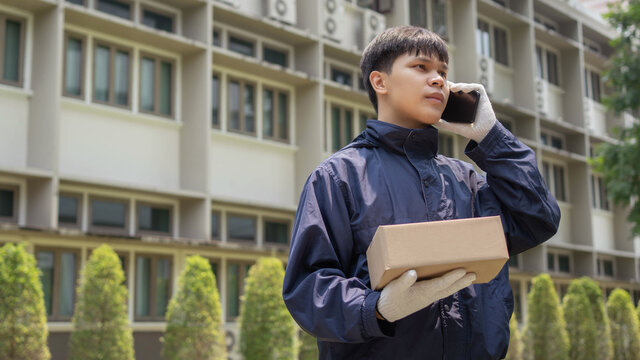 Parcel Delivery Concept The Mail Carrier Standing In Front Of The Building And Calling His Customer To Confirm The Right Address For Distributing The Parcel Post