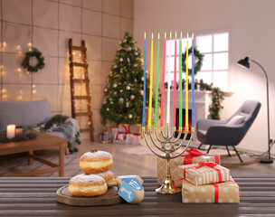 Obraz na płótnie Canvas Menorah, gifts, donuts for Hanukkah and dreidels on table in room decorated for Christmas