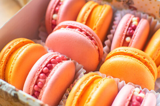 Sweet, tender and bright raspberries and orange macarons in a gift box. French dessert.