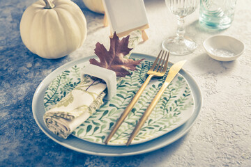 Place setting for Thanksgiving in vintage style with pumpkins and autumn leaf