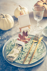 Place setting for Thanksgiving in vintage style with pumpkins and autumn leaf