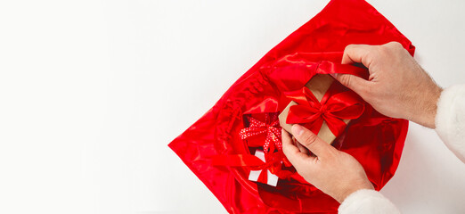 Santa Claus, Saint Nicholas packing presents gift boxes in sack bag. Merry Christmas shipping delivery concept.