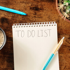 To do list. Overhead square shot of a turquoise blue pen and a notebook on a wooden desk. The...