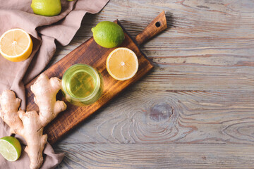 Glass of tasty drink with citrus fruits and ginger on wooden background