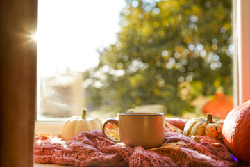 Autumn still life, Cup of hot tea, pumpkins,falling leaves and scarf on the windowsill
