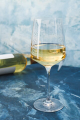 Glass of white wine on color background