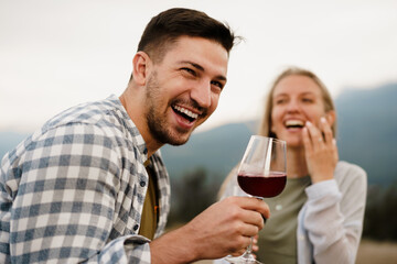 Smiling couple toasting wine glasses outdoors in mountains