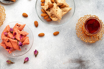 Assortment of Turkish delights with glass of tea on gray background