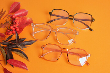eye glasses nad red autumn leaves on orange background copy space