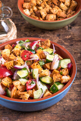 Italian vegetarian panzanella salad in a bowl on a table with croutons, close-up
