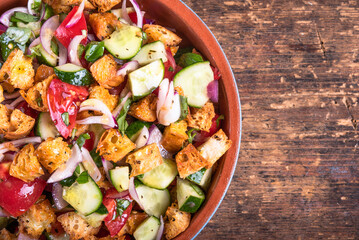 Italian vegetarian panzanella salad in bowl on table with croutons, close-up, top view, copy space