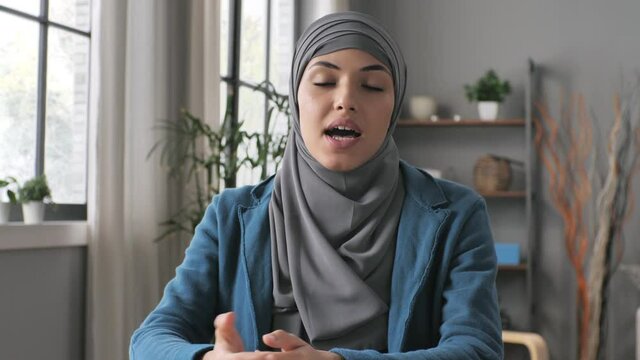 Front view of muslim woman doing a remote application job interview listening and talking to the camera,portrait of arab young female listens and speaking in video conference call