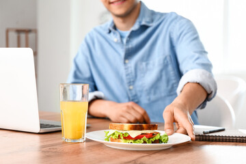 Young man with tasty sandwich in office